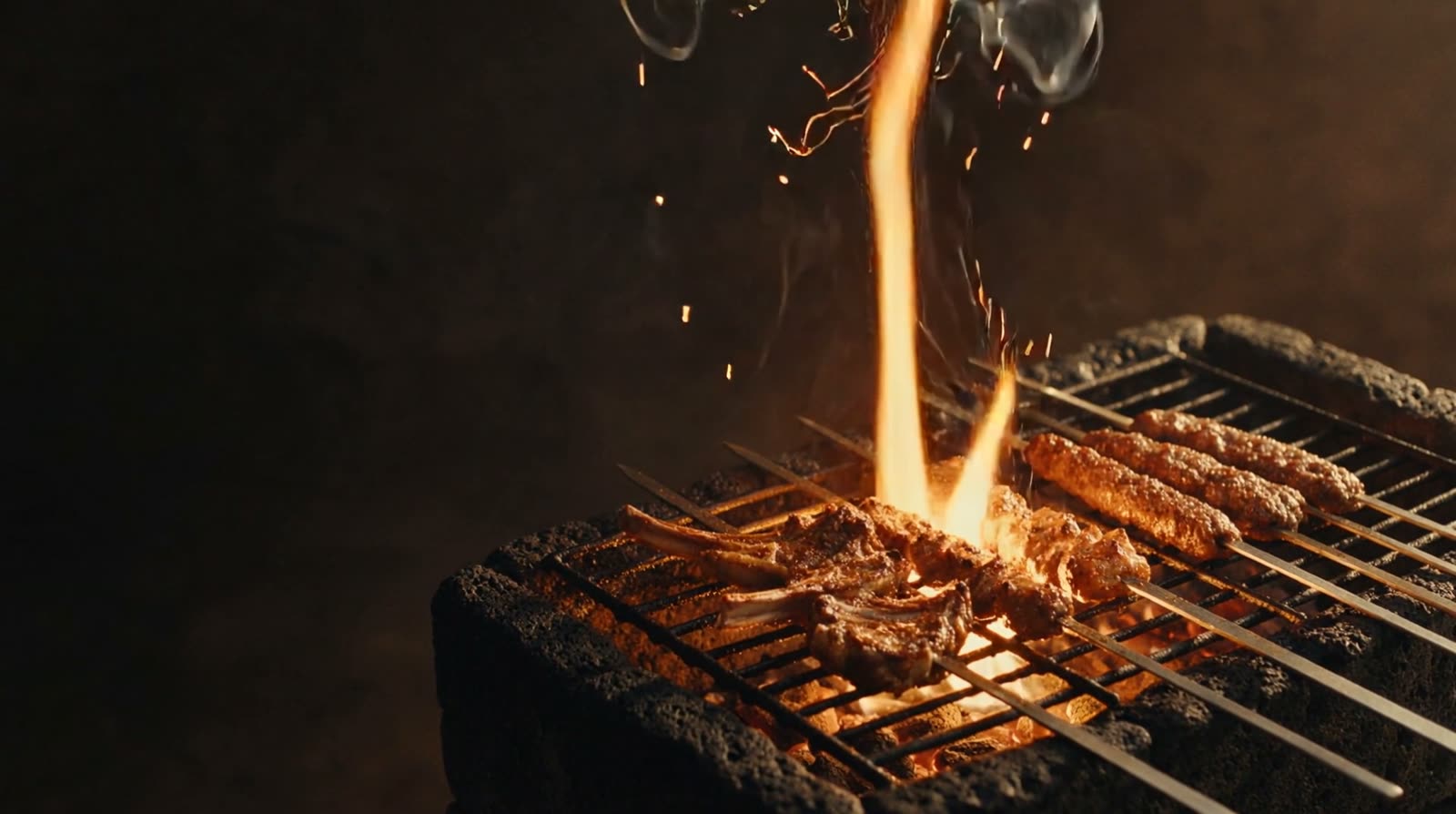 Lamskotletten en kebabspiesen boven oplaaiende vlammen op de lavagrill.